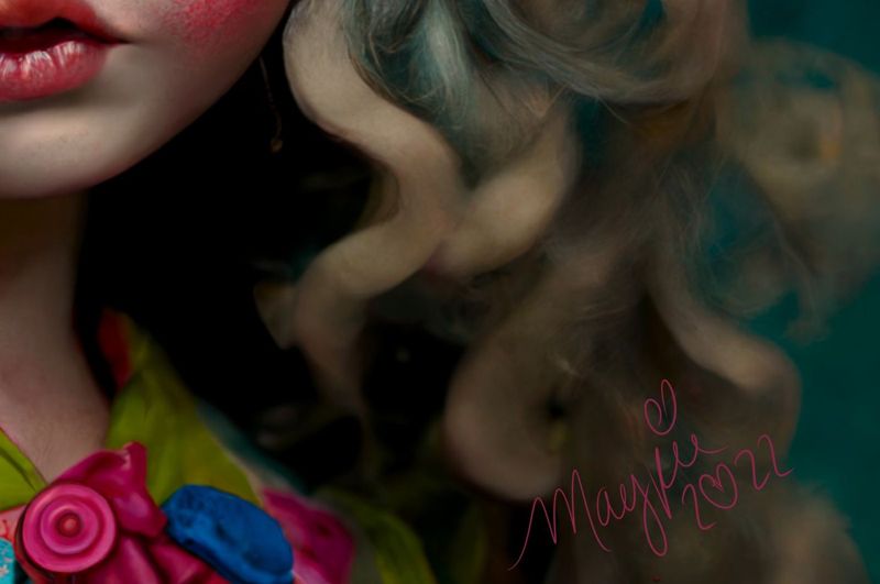 Close up of the lower right: pale curls over a lime and pink floral collar with a pink button, and the Magpie 2022 signature in pink script.