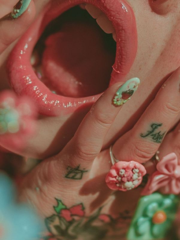 Close up detail of the open mouth and stretched pink features merging with small blue and pink flowers.
