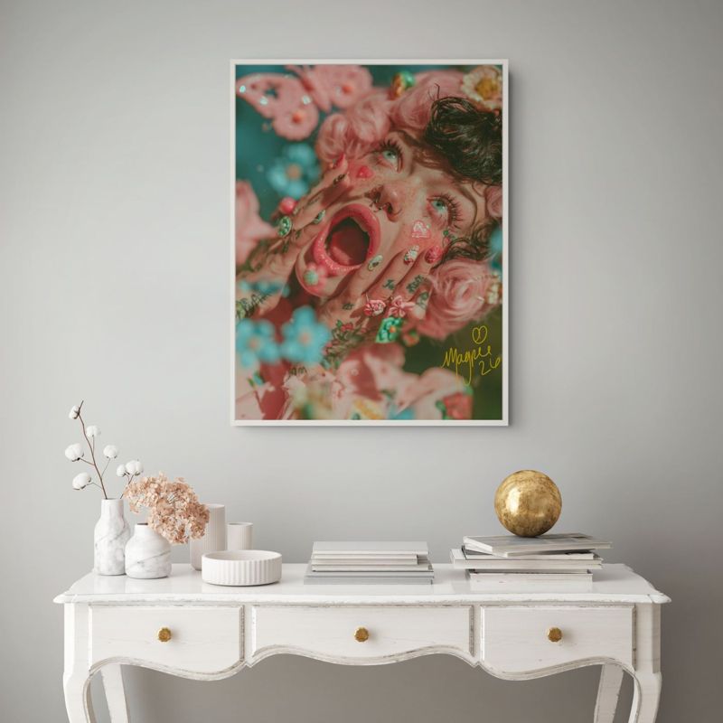 The screaming flowers print hung on a grey wall above a white French console table with white vases and a gold globe.