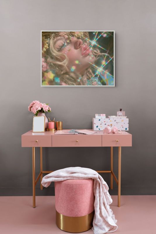 The rainbow sparkle girl print hung on a dark grey wall above a blush desk with gold legs and a pink velvet stool.