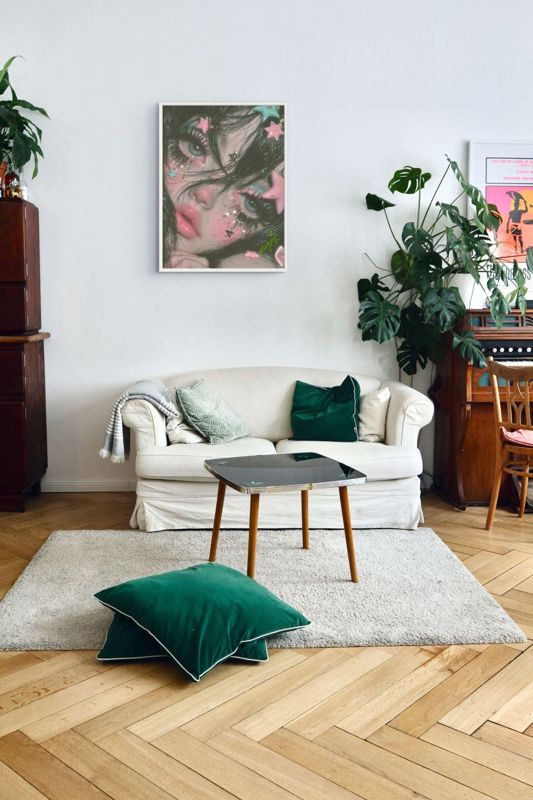 The star face print hung above a white sofa with green cushions on a herringbone wood floor, plants around.