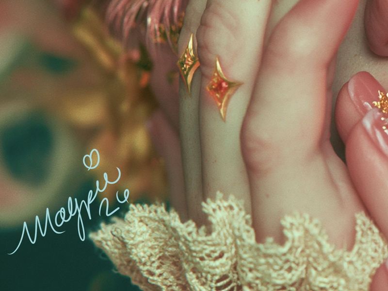 Close up of the lower left corner: pale lace, pink and cream ruffles with the Magpie signature in pink script.
