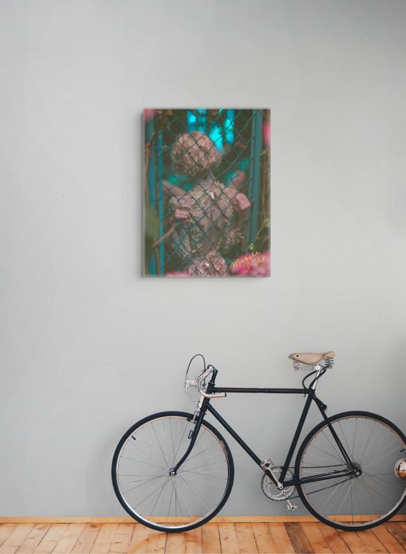 The teal and pink chain link fence print hung on a pale grey wall above a vintage black bicycle leaning on a wood floor.