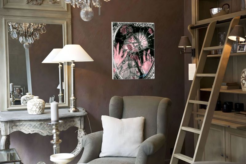 The shattered mirror print on a dark taupe wall in an elegant sitting room with a gilt mirror, white table lamps, a grey wingback chair and a library ladder.