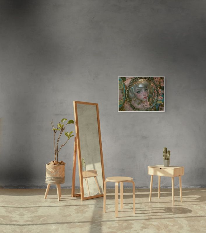 The girl in the glass mirror print hung on a white paneled wall above a small green velvet armchair.