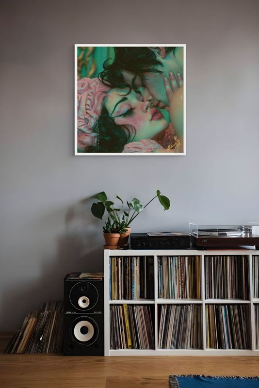 The lovers kiss print hung on a grey wall above shelves of records with a speaker and a grey bed.