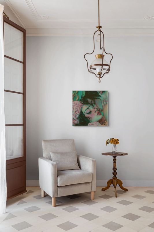The lovers kiss print hung on a white wall above a cream armchair with a pendant lamp and a checkered floor.