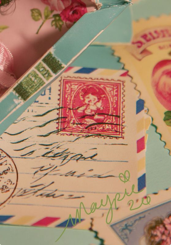 Close-up detail of a red vintage stamp showing a girl figure, airmail envelope stripes in blue, red, and yellow, cursive handwriting, a circular postmark, and the Magpie signature in green script.