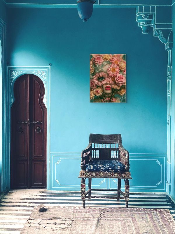 Portrait art print of a surreal floral cyclops girl on a vibrant turquoise wall with white ornamental molding, beside a dark Moroccan arched door, with an ornate carved chair below.