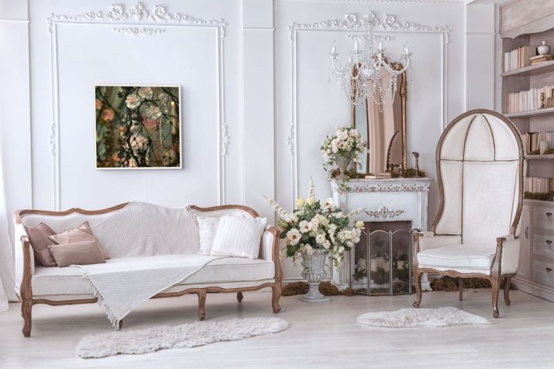 The wire branches and pearls print hung in a white room above a white sofa with a birdcage chair and a mirror.
