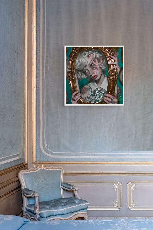 The girl in the gold frame print hung on a pale blue silk wall with gilt trim above a blue French armchair.