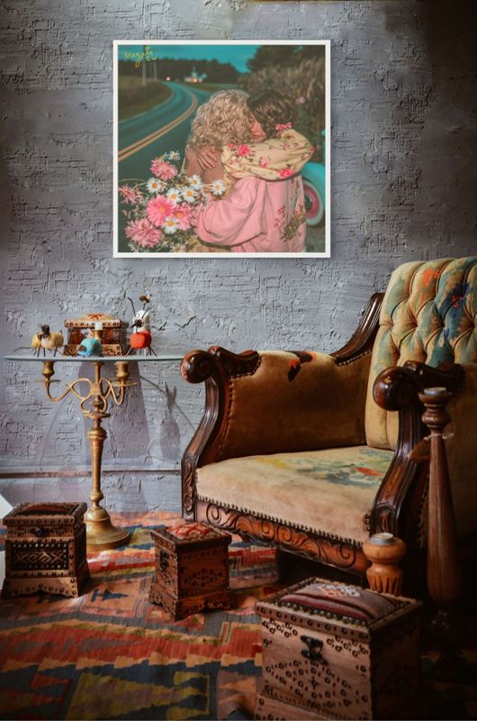 The roadside hug print hung on a grey brick wall above an antique carved armchair, a brass candle stand and a patterned rug.