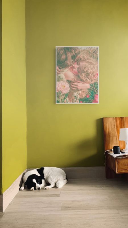 The friends in the flower field print hung on an olive green wall above a wooden cabinet with a sleeping dog.